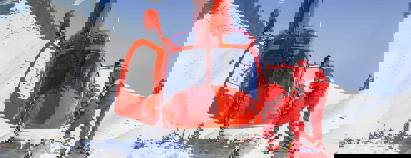 Rescue helicopter landed on a snowy mountainside with two emergency responders