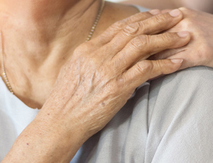 Close-up of one person’s hand resting on another person’s shoulder