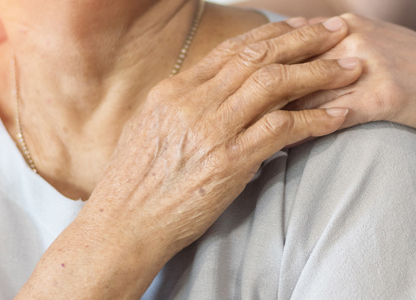 Close-up of one person’s hand resting on another person’s shoulder