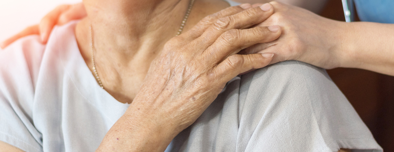 Close-up of one person’s hand resting on another person’s shoulder