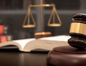 Judge’s gavel resting on a sound block with legal books and scales of justice in the background