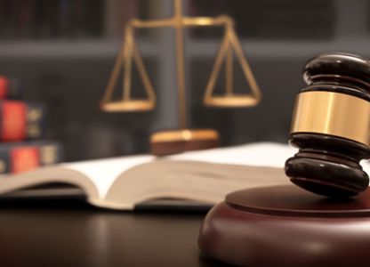 Judge’s gavel resting on a sound block with legal books and scales of justice in the background