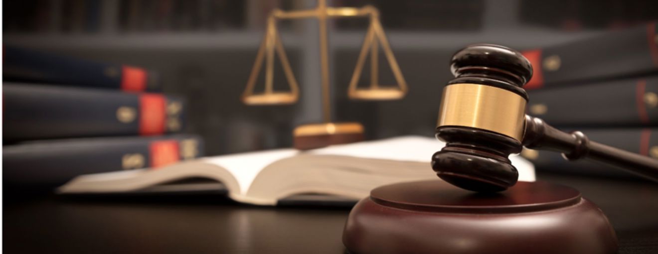 Judge’s gavel resting on a sound block with legal books and scales of justice in the background