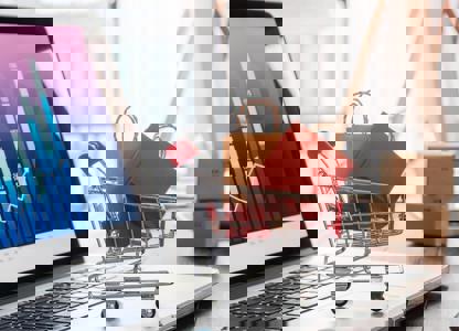 Small shopping trolley graphic filled with packages placed on a laptop displaying data charts