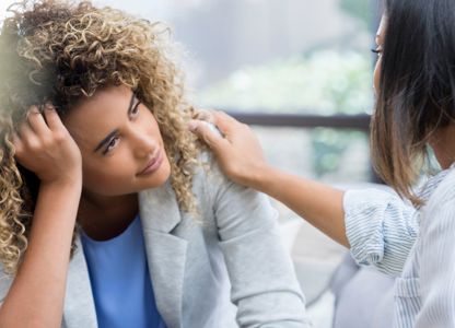 Person comforting someone who is distressed, with a hand placed supportively on their shoulder