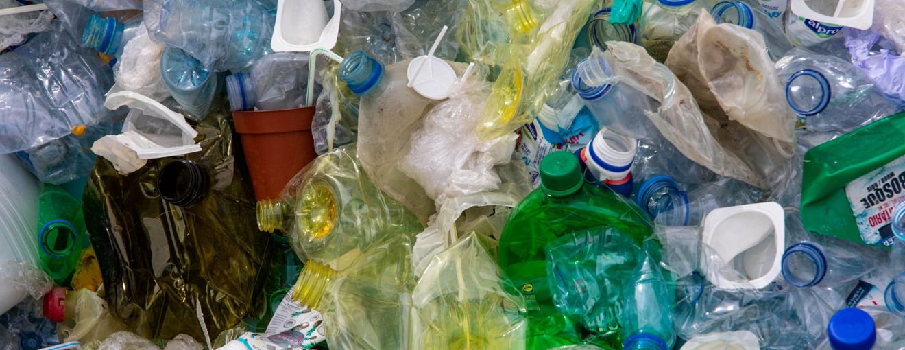 Pile of mixed plastic waste including bottles, containers, and packaging materials