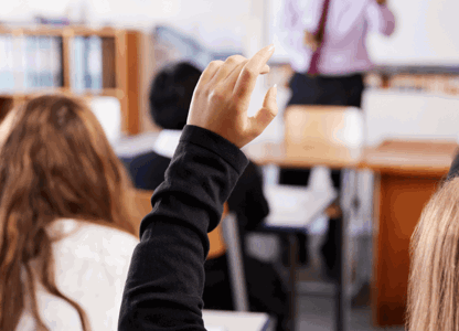 Students in a classroom with their hands raised