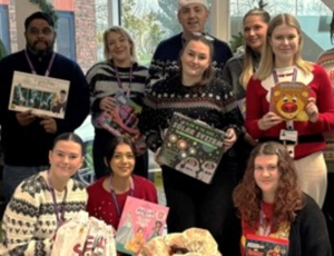 Procurement services team in festive jumpers holding christmas donations 