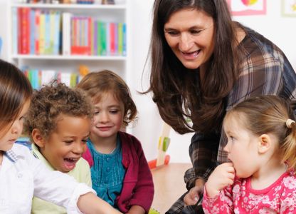 Teacher interacting with a small group of young children in a colourful classroom setting