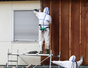 People wearing full protective suits surrounded by construction debris