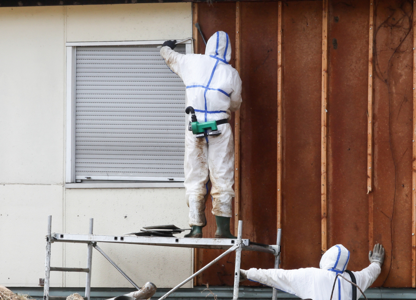 People wearing full protective suits surrounded by construction debris