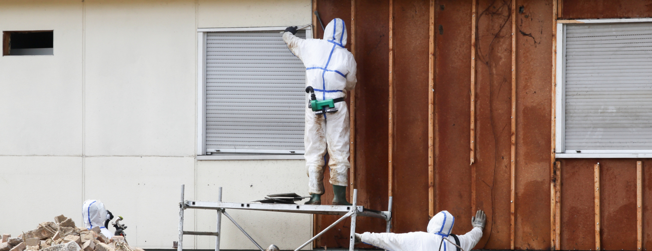 People wearing full protective suits surrounded by construction debris