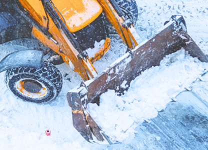 Front loader clearing snow on a snowy road surface