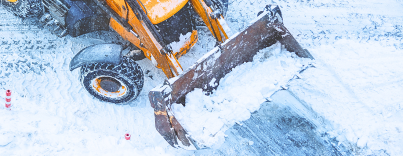 Front loader clearing snow on a snowy road surface